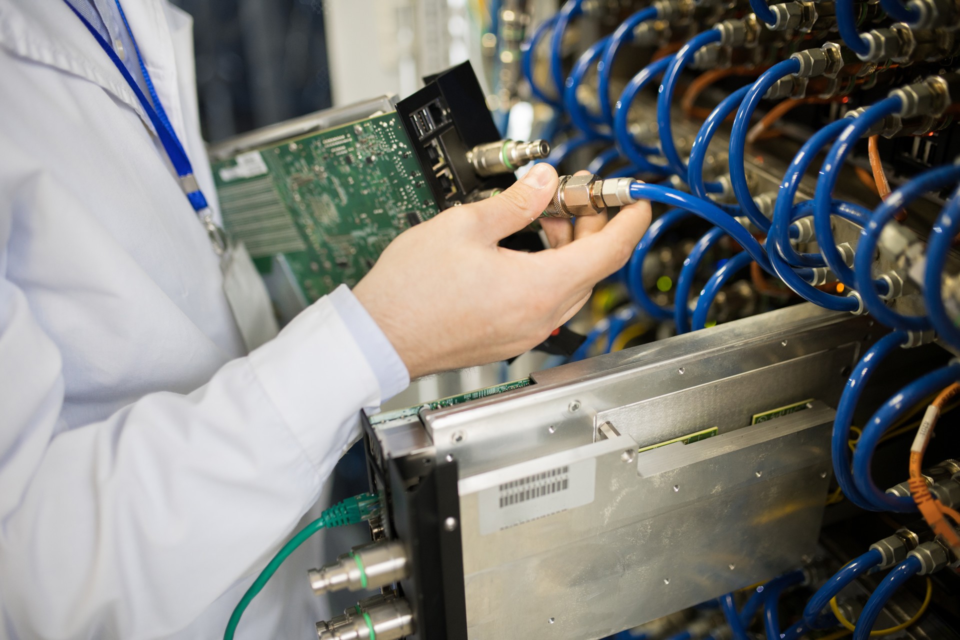 Close-up of unrecognizable network server engineer plugging patch cable in network switch of hardware equipment at mining farm